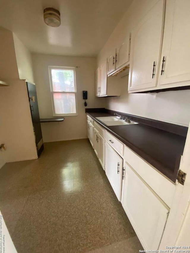 2019 Martin Luther King Dr, San Antonio, TX 78203 - kitchen featuring white cabinets, a sink, dark floors, and dark countertops