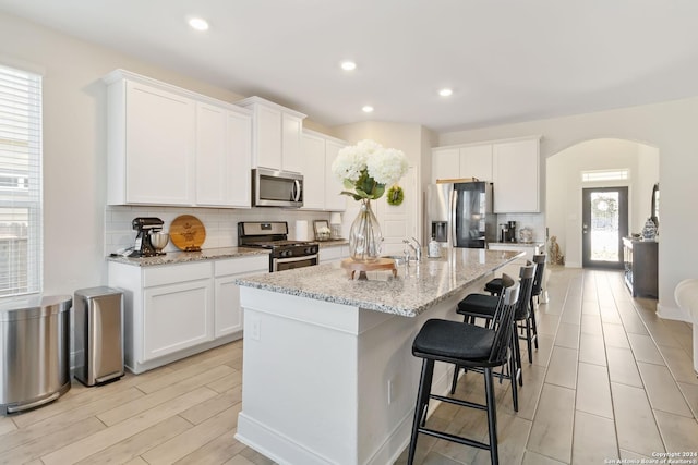 3443 Iron Cyn, Bulverde, TX 78163 - kitchen with arched walkways, backsplash, appliances with stainless steel finishes, and an island with sink