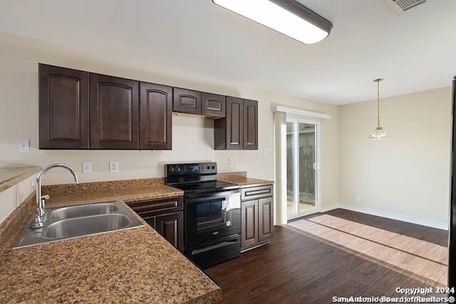 kitchen featuring black electric range, decorative light fixtures, dark brown cabinetry, dark hardwood / wood-style floors, and sink