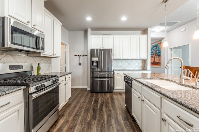 kitchen with white cabinetry, dark hardwood / wood-style floors, appliances with stainless steel finishes, and hanging light fixtures