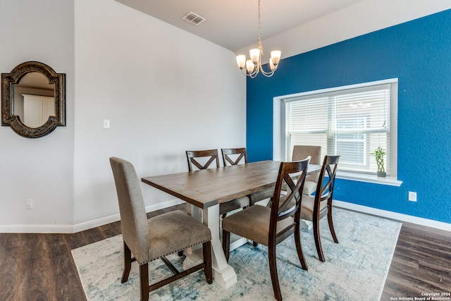 dining room with dark wood-type flooring and a chandelier