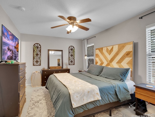 carpeted bedroom with ceiling fan and a textured ceiling