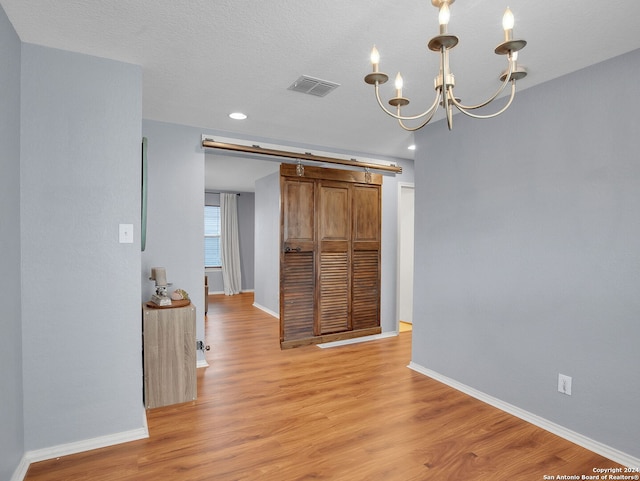 unfurnished dining area featuring a textured ceiling, light hardwood / wood-style flooring, and a chandelier