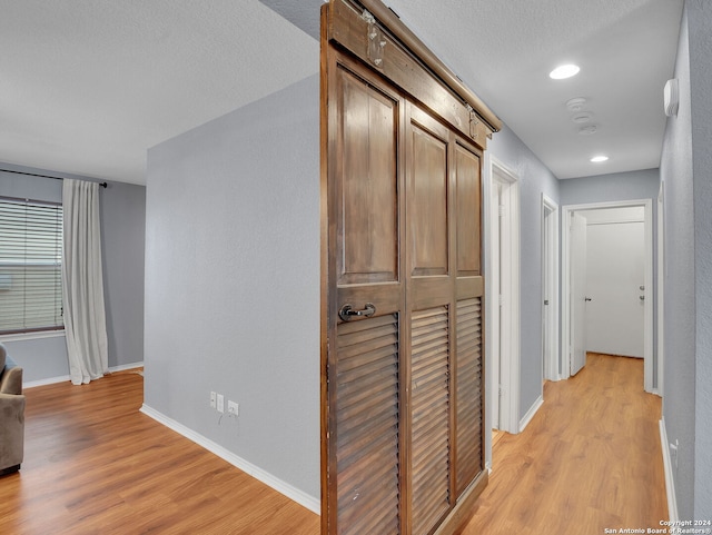 corridor featuring a textured ceiling and light hardwood / wood-style floors