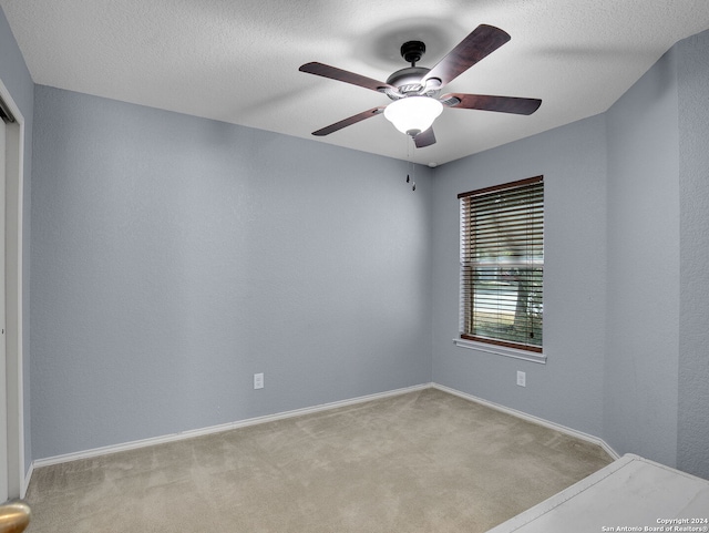 unfurnished bedroom featuring ceiling fan, a textured ceiling, and light carpet