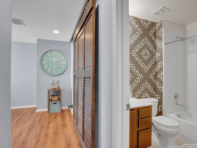 full bathroom featuring a textured ceiling,  shower combination, hardwood / wood-style floors, vanity, and toilet