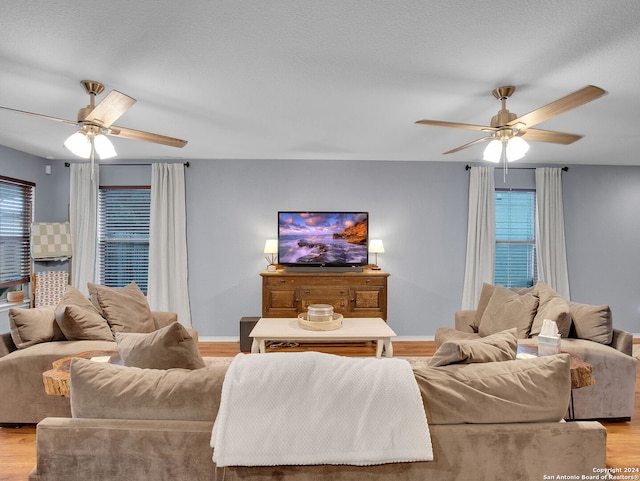 living room featuring light hardwood / wood-style flooring, ceiling fan, and a healthy amount of sunlight