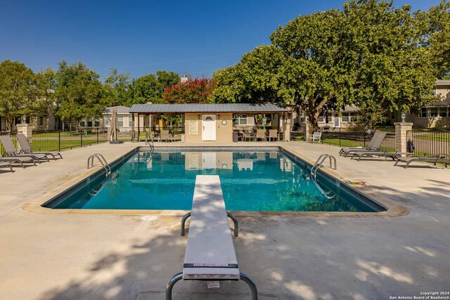 view of swimming pool with a diving board and a patio area