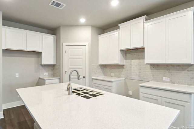 kitchen featuring white cabinets and a center island with sink