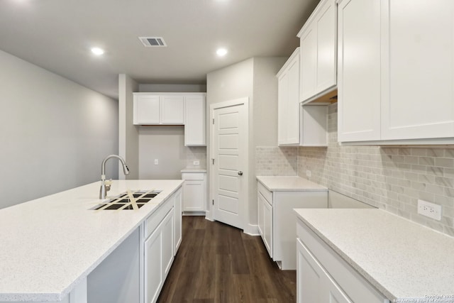 kitchen with sink, dark hardwood / wood-style floors, an island with sink, and white cabinets