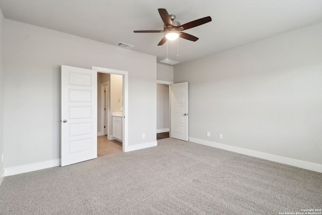 unfurnished bedroom featuring ensuite bathroom, light colored carpet, and ceiling fan