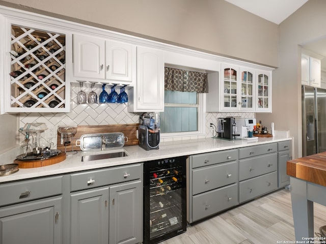 kitchen with white cabinets, wine cooler, stainless steel fridge, backsplash, and gray cabinets