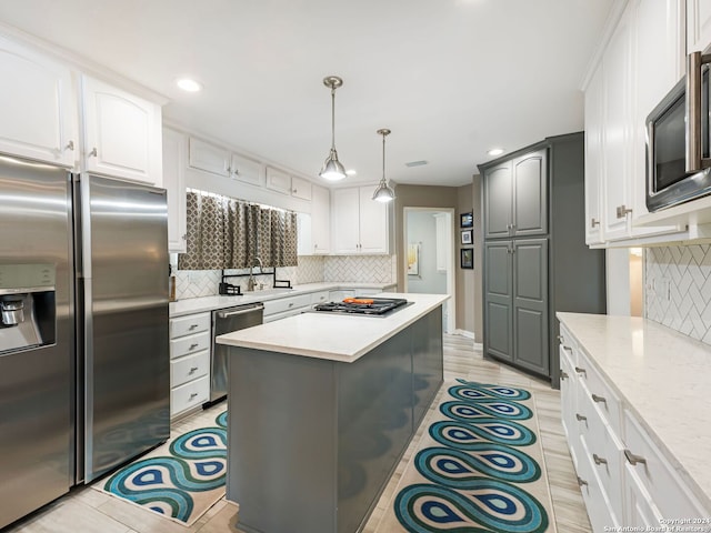 kitchen featuring light hardwood / wood-style flooring, appliances with stainless steel finishes, hanging light fixtures, and decorative backsplash