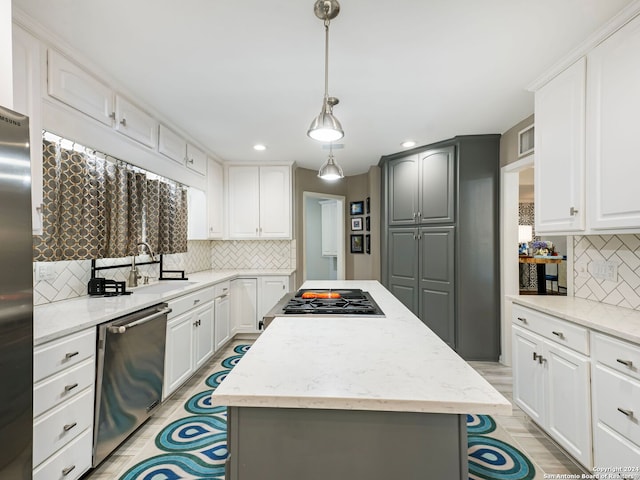 kitchen with a kitchen island, sink, appliances with stainless steel finishes, gray cabinets, and backsplash