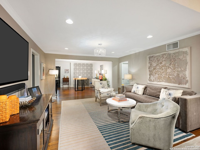 living room with wood-type flooring, ornamental molding, and a notable chandelier