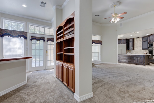 interior space featuring ornamental molding, dark brown cabinetry, light colored carpet, and appliances with stainless steel finishes