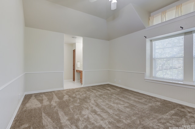 carpeted spare room with ceiling fan and vaulted ceiling