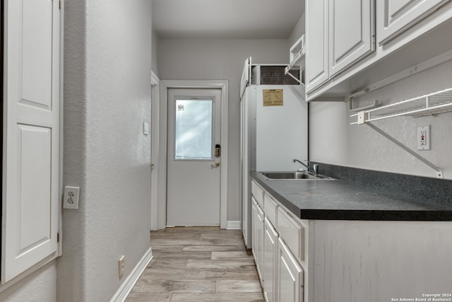 kitchen with light hardwood / wood-style floors, white cabinetry, and sink