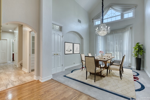 dining space featuring a chandelier, light hardwood / wood-style floors, and high vaulted ceiling