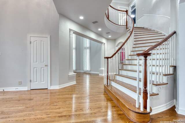 stairway with wood-type flooring and ornate columns