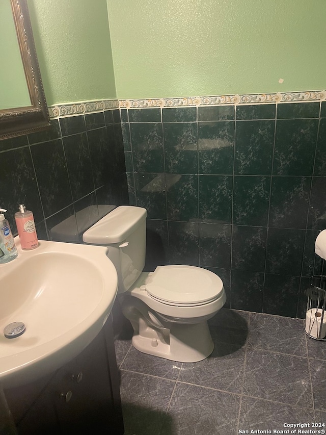 bathroom with tile walls, sink, tile patterned floors, and toilet