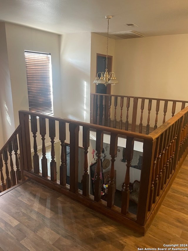 stairs featuring wood-type flooring and an inviting chandelier