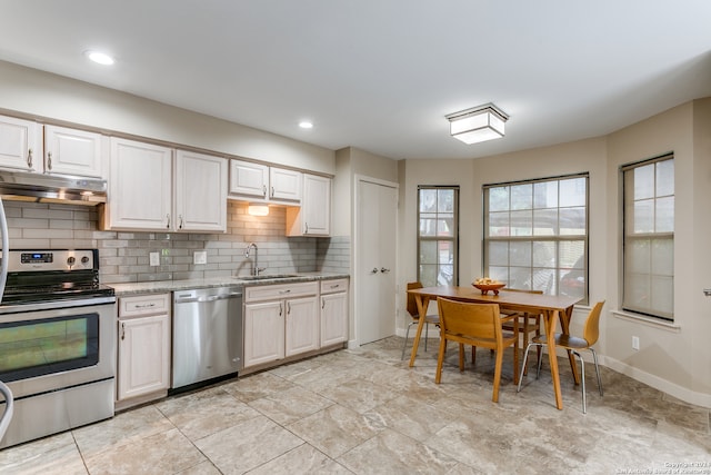 kitchen with light stone countertops, backsplash, appliances with stainless steel finishes, and sink