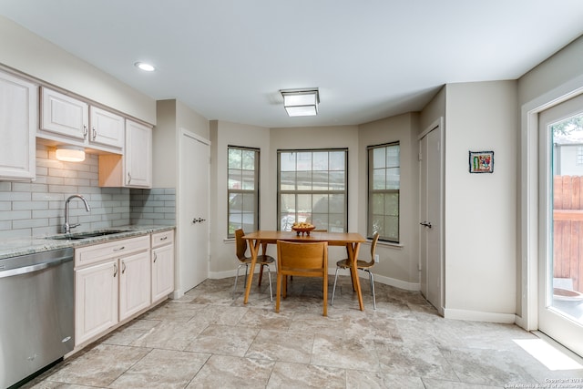 kitchen with backsplash, dishwasher, light stone counters, and sink