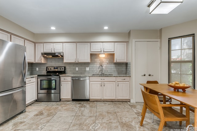 kitchen featuring appliances with stainless steel finishes, light stone countertops, backsplash, and sink