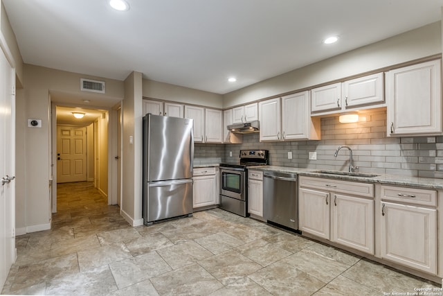 kitchen featuring light stone counters, appliances with stainless steel finishes, tasteful backsplash, and sink