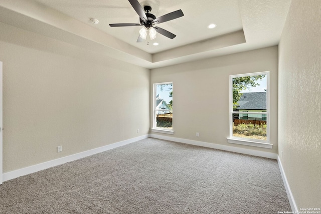 unfurnished room with ceiling fan, carpet floors, and a tray ceiling