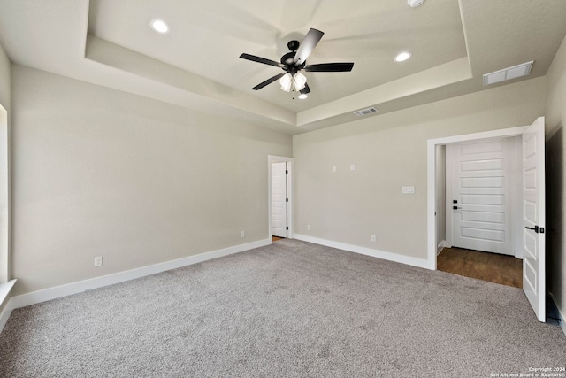 unfurnished bedroom featuring carpet, ceiling fan, and a raised ceiling