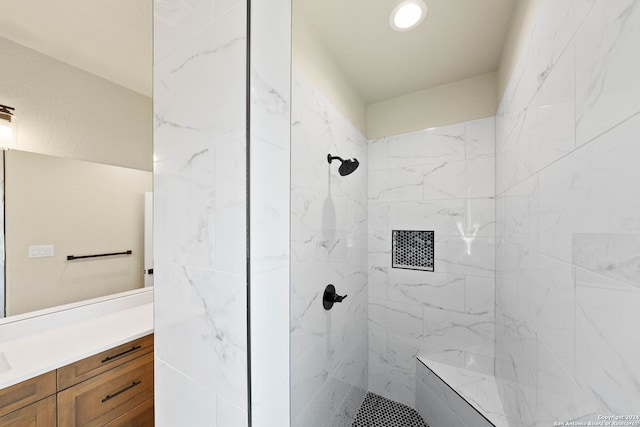 bathroom with a tile shower and vanity