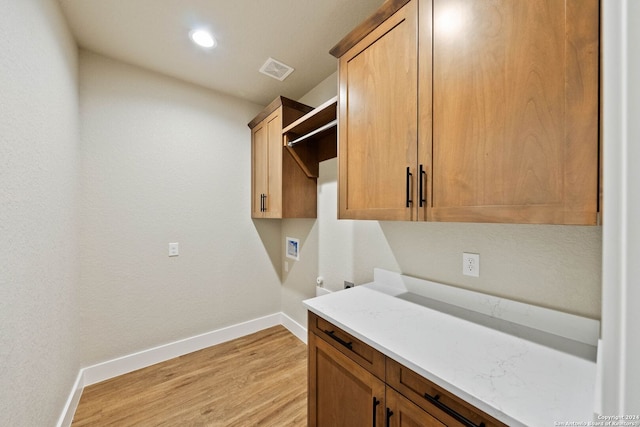 clothes washing area with washer hookup, cabinets, and light hardwood / wood-style flooring