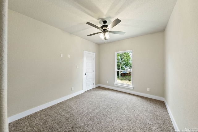 carpeted empty room featuring ceiling fan and a textured ceiling