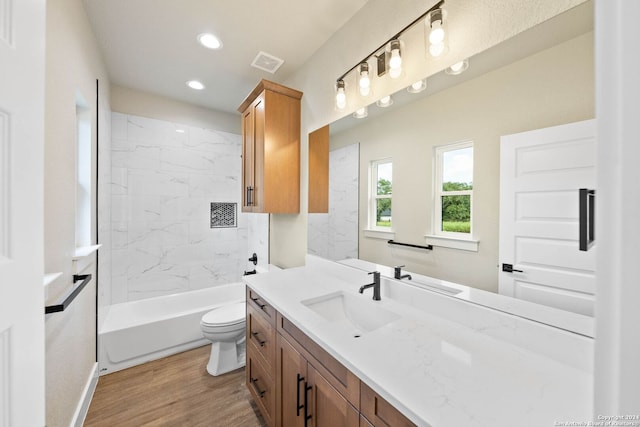 full bathroom with wood-type flooring, tiled shower / bath combo, vanity, and toilet