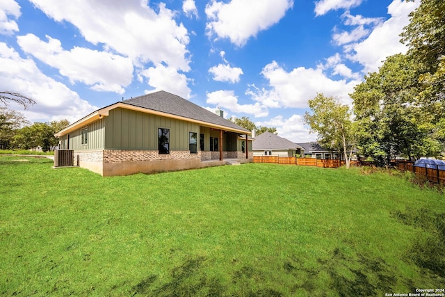 rear view of property with a lawn and central air condition unit