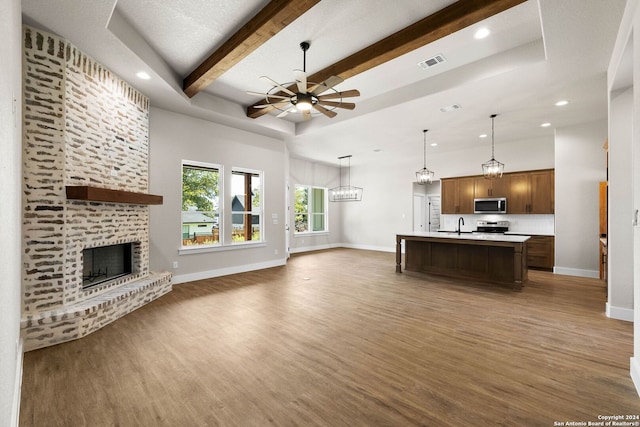 living room featuring a fireplace, beam ceiling, dark hardwood / wood-style floors, and ceiling fan