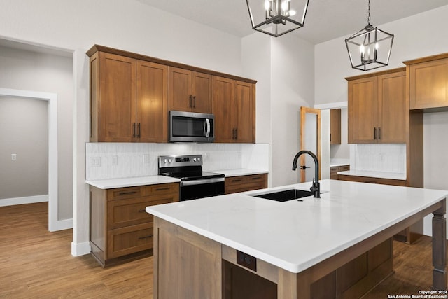 kitchen featuring appliances with stainless steel finishes, a center island with sink, sink, and pendant lighting