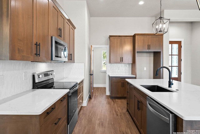 kitchen with light hardwood / wood-style floors, sink, hanging light fixtures, stainless steel appliances, and light stone countertops