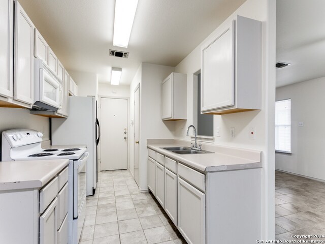 kitchen featuring light tile patterned floors, white cabinets, sink, and white appliances