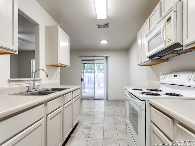 kitchen with white appliances, white cabinetry, light tile patterned floors, and sink