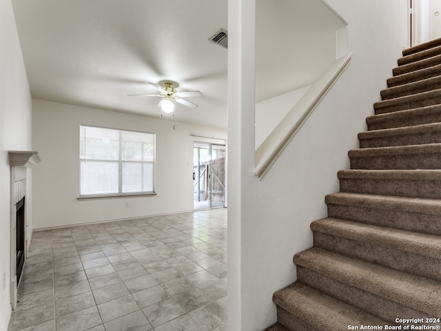 stairway featuring ceiling fan and tile patterned flooring