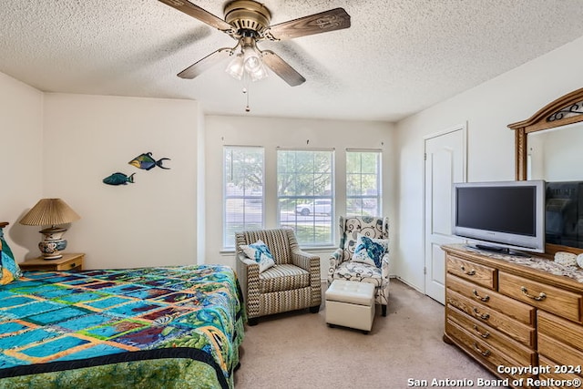 bedroom with a textured ceiling, ceiling fan, and light colored carpet