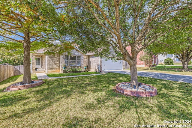 view of property hidden behind natural elements with a garage and a front lawn