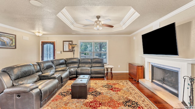 living room featuring ceiling fan, a textured ceiling, a tray ceiling, dark hardwood / wood-style floors, and crown molding