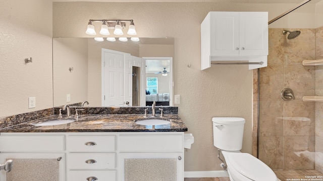 bathroom featuring a tile shower, vanity, toilet, and ceiling fan