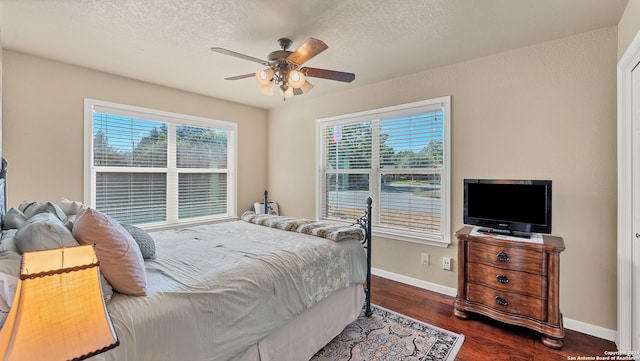 bedroom featuring a textured ceiling, dark wood-type flooring, and ceiling fan