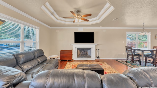 living room featuring a tray ceiling, ceiling fan, hardwood / wood-style floors, and crown molding