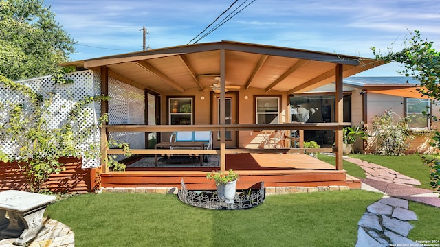 back of house featuring a lawn, ceiling fan, and a wooden deck